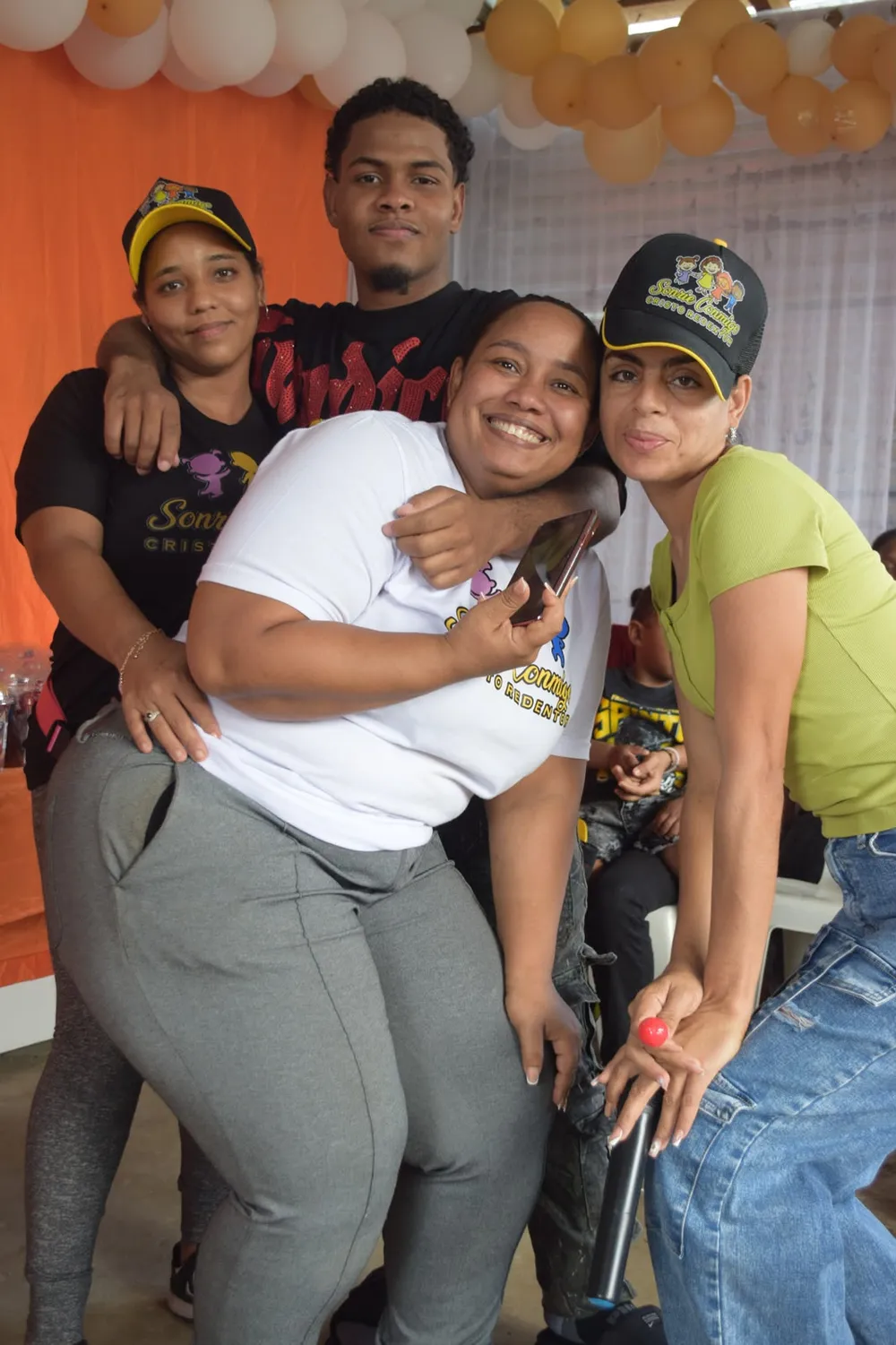Voluntarios con gorras de Sonríe Conmigo abrazándose con alegría